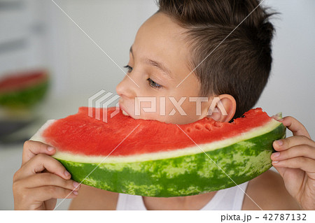 Caucasian boy with expressive eyes, taking a bite of a juicy watermelon Caucasian boy with expressive eyes, taking a bite of a juicy watermelon 42787132