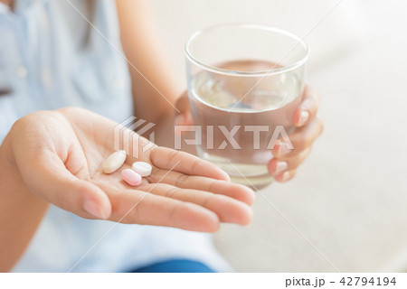 Woman hand with pills medicine and glass of water Woman hand with pills medicine and glass of water 42794194