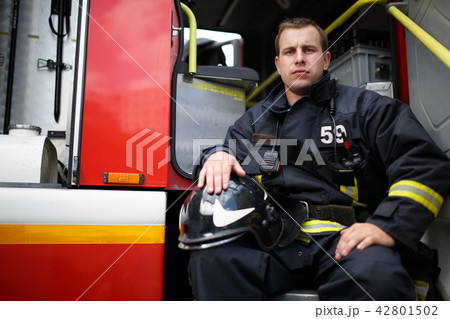 Photo of young fireman looking at camera in fire truck 42801502