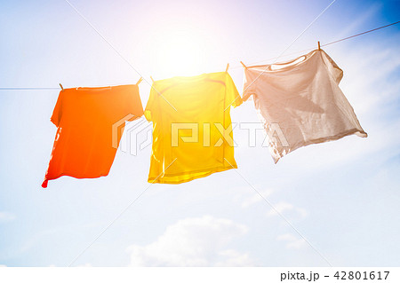 Photo of three T-shirts hanging on rope against blue sky background 42801617
