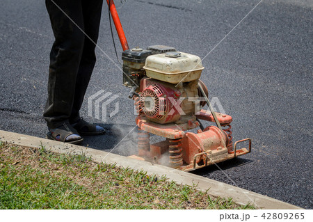 Worker uses vibratory plate compactor Worker uses vibratory plate compactor 42809265