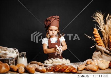 Little girl kneading dough at table 42811906