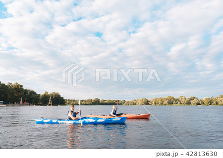Husband sitting in blue canoe rowing near his woman in red canoe Husband sitting in blue canoe rowing near his woman in red canoe 42813630