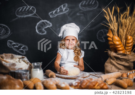 Little girl kneading dough at table Little girl kneading dough at table 42823198
