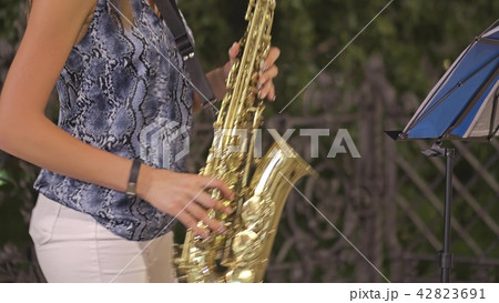 Unrecognizable young woman playing saxophone on the street Unrecognizable young woman playing saxophone on the street 42823691