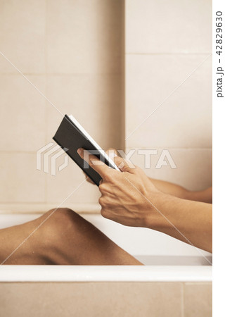 young man reading a book in the bathtub 42829630