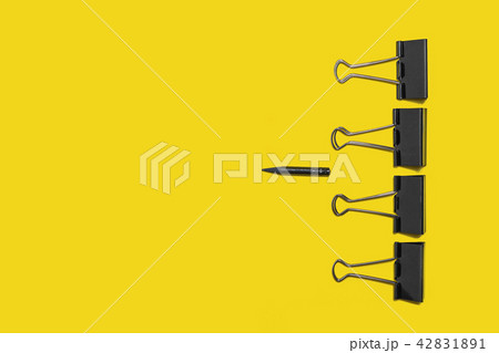 four big paper clips against little pencil 42831891