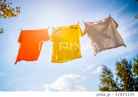 Photo of three T-shirts hanging on rope against blue sky background 42835535