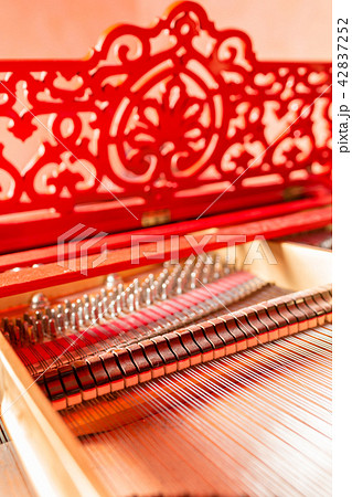 Strings inside a red grand piano. Piano playing, dampers, felt hammers, bronze strings and metal 42837252