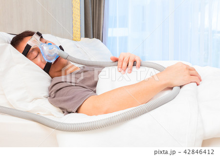 Asian man wearing CPAP mask, connecting to hose Asian man wearing CPAP mask, connecting to hose 42846412