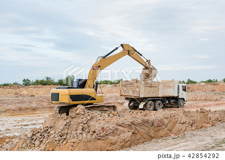Yellow excavator machine loading soil into a dump  42854292