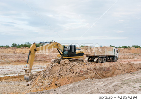 Yellow excavator machine loading soil into a dump Yellow excavator machine loading soil into a dump 42854294