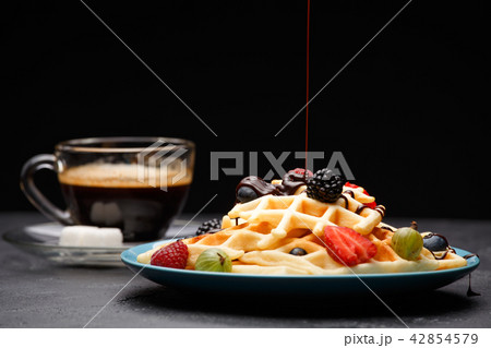 Photo of cup of black coffee with sugar with Viennese waffles with strawberries, raspberries Photo of cup of black coffee with sugar with Viennese waffles with strawberries, raspberries 42854579