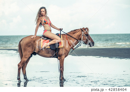 Woman fashion model riding a horse on the beach. Woman fashion model riding a horse on the beach. 42858404