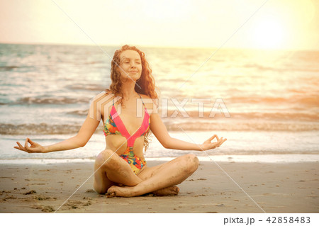 Young woman practices yoga on the beach in summer. 42858483