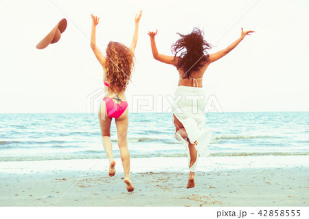 Happy women jumping on sand beach in summer. 42858555