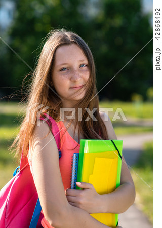Girl schoolgirl in summer in park in nature. Hands holding a notebook of a folder behind a backpack Girl schoolgirl in summer in park in nature. Hands holding a notebook of a folder behind a backpack 42868492