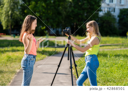 Where little teenage girls in the summer in park are recording video on the camera. Emotionally 42868501