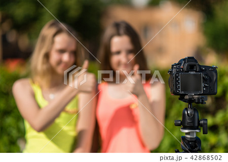 Two teenage girls, in summer in the park, are recording video on the camera. Blurred background free Two teenage girls, in summer in the park, are recording video on the camera. Blurred background free 42868502