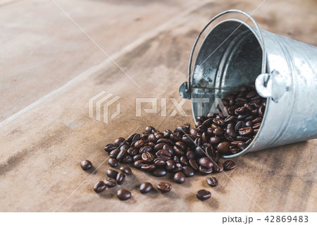 Coffee beans in a metal bucket on wooden floor 42869483