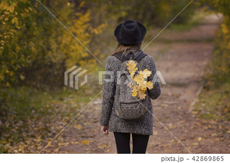 Yellow leaves in a backpack, a girl stands Yellow leaves in a backpack, a girl stands 42869865