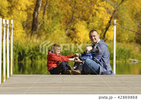 Father and two sons play on the pier. Autumn 42869868
