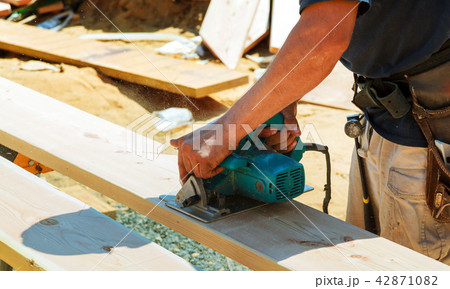 Closeup of a carpenter using a circular saw to cut 42871082