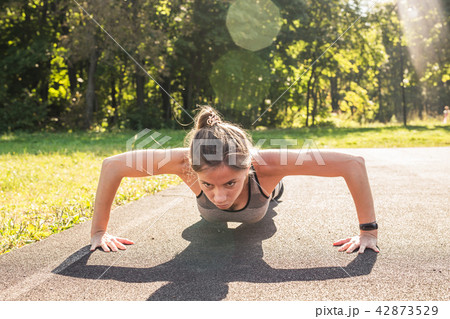 Fitness woman doing push-ups during outdoor cross training workout. Beautiful young and fit fitness 42873529