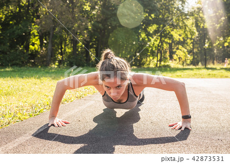 Fitness woman doing push-ups during outdoor cross training workout. Beautiful young and fit fitness 42873531