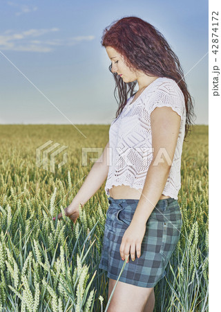 Young girl standing in a cornfield 42874172