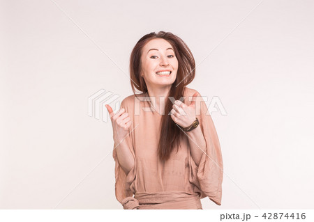 Fashion, style and gesture concept - happy smiling young woman over white background showing thumbs Fashion, style and gesture concept - happy smiling young woman over white background showing thumbs 42874416
