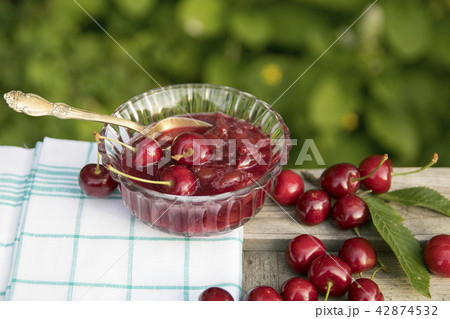 Fresh sweet cherries and marmalade bowl with teaspoon 42874532