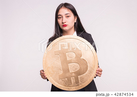 Sad brunette girl with big bitcoin on white background Sad brunette girl with big bitcoin on white background 42874534