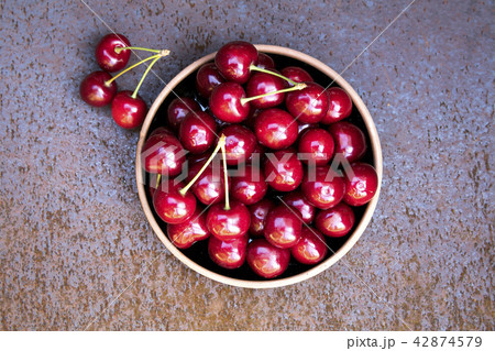 Fresh sweet cherries bowl on grunge rust background 42874579