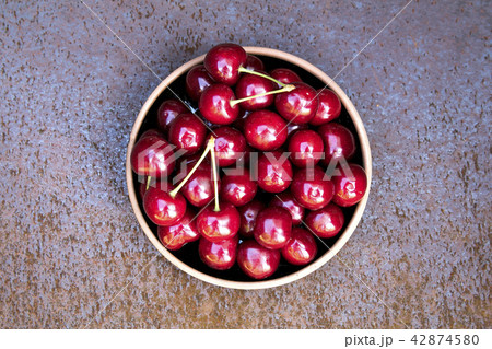 Fresh sweet cherries bowl on grunge rust background 42874580
