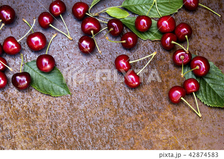 Fresh sweet cherries bowl with leaves on grunge rust background 42874583