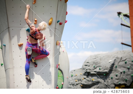 Photo from back of sports blonde with short haircut in sportswear on workout at wall for rock 42875603
