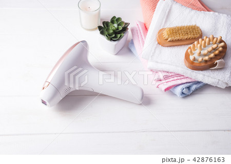 set of means of hair removal. Modern epilators in bathroom on a white wooden background. 42876163