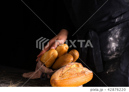 Baker woman holding rustic organic loaf of bread in hands - rural bakery. Natural light, moody still 42876220