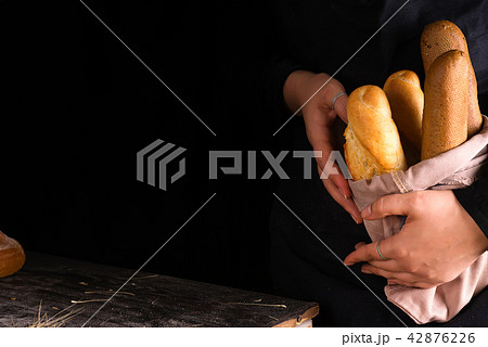 Woman holding tasty fresh bread sorts on a dark 42876226