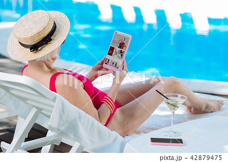 Modern blonde-haired mature woman shopping online using laptop Modern blonde-haired mature woman shopping online using laptop 42879475