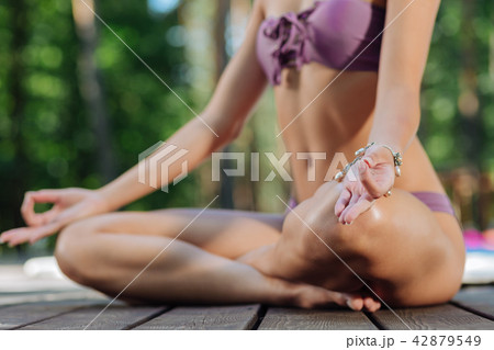 Slim woman sitting in lotus pose while meditating outdoors 42879549