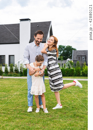 Delighted positive family standing near their house 42880121