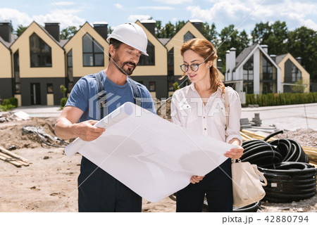 Pleasant young businesswoman looking at the building plan Pleasant young businesswoman looking at the building plan 42880794