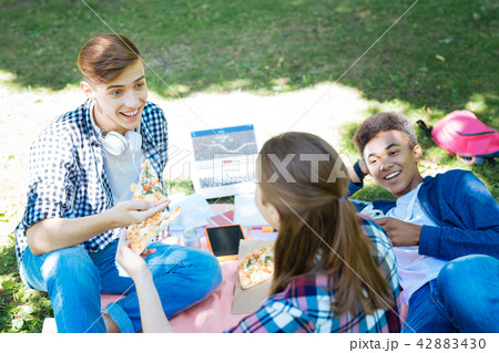 Three active students having pizza break while working on project 42883430