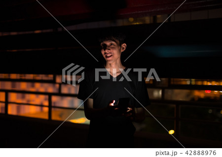 Portrait Of Asian Man Outdoors At Night In Parking Lot Using Mobile Phone 42888976