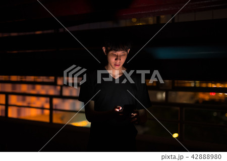 Portrait Of Asian Man Outdoors At Night In Parking Lot Using Mobile Phone 42888980