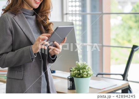 vBusinesswoman standing with smile using tablet vBusinesswoman standing with smile using tablet 42894245