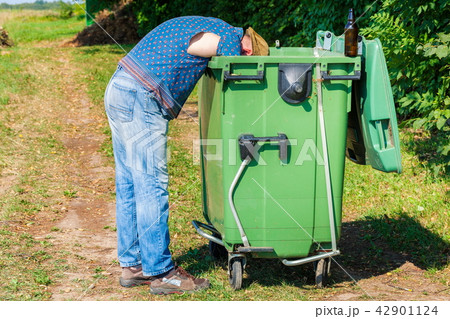 Homeless looking for food in waste container 42901124