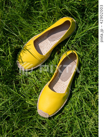 Yellow fashionable espadrilles on green grass Yellow fashionable espadrilles on green grass 42902003